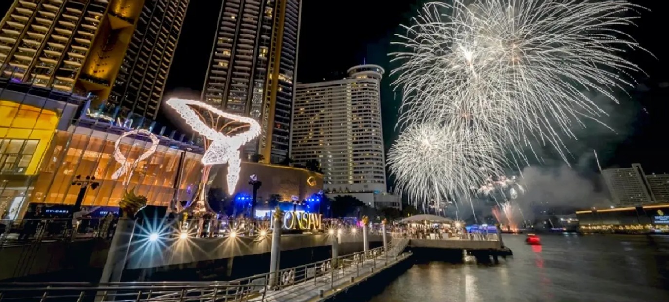 Fireworks over the ICONSIAM riverfront in Bangkok at night for the Serpenti Light Up, with crowds gathered on the pier and golden illuminated towers behind
